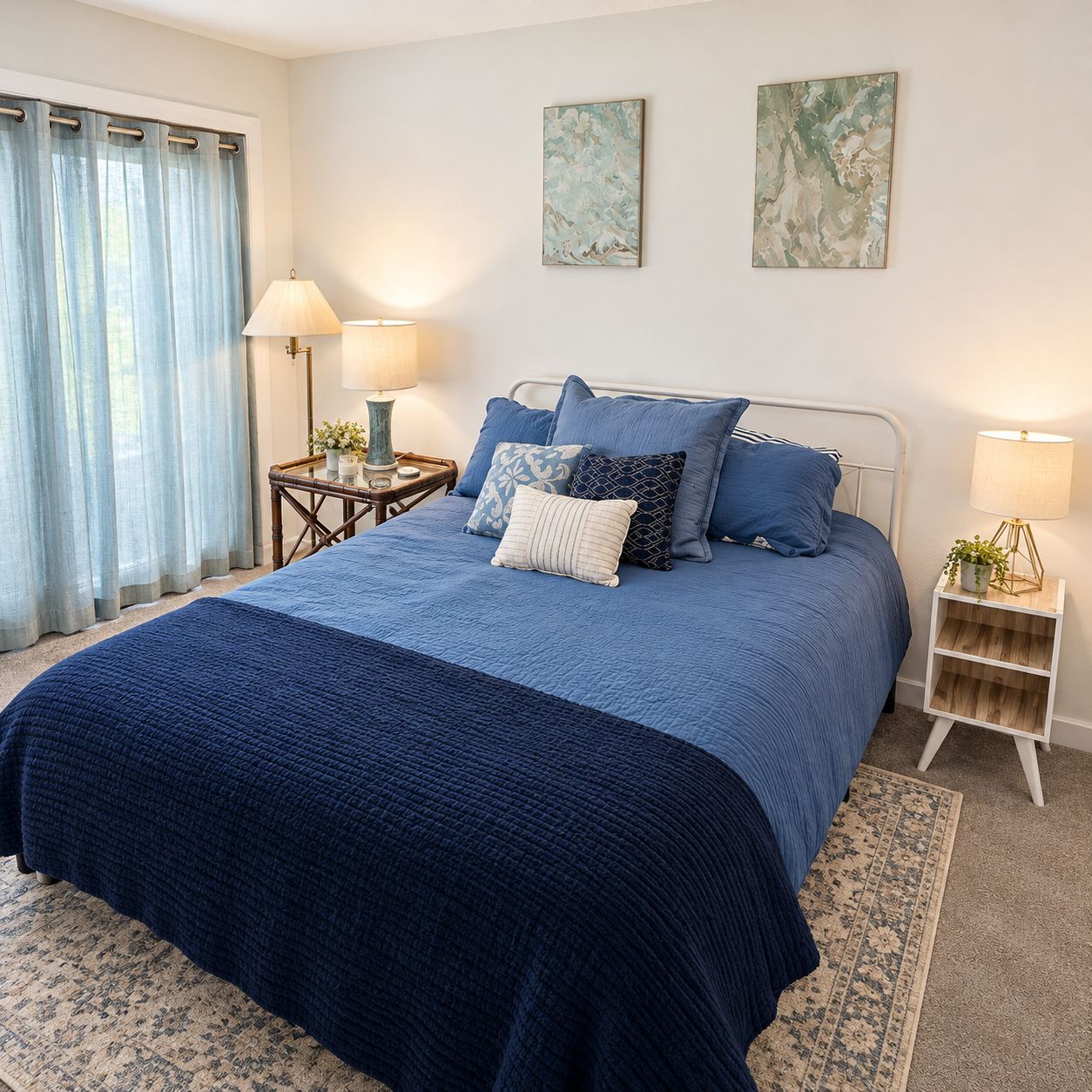 A bedroom with a bed, two bedside tables, a lamp, a rug, and a window with curtains.