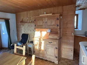 A wooden interior with a dining table, a chair, a cabinet with drawers, and a window. - Turmhaus Giovanoli, (Tschlin) by Interhome (Tschlin)