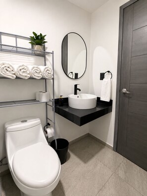 A modern bathroom with a toilet, sink, and mirror. - Gupy 26 - 3BR house steps from de beach  (Cancún)