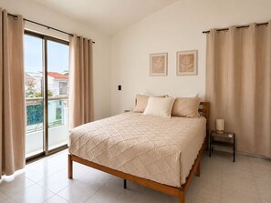 A bedroom with a bed, curtains, a nightstand, and two framed pictures on the wall. - Gupy 26 - 3BR house steps from de beach  (Cancún)
