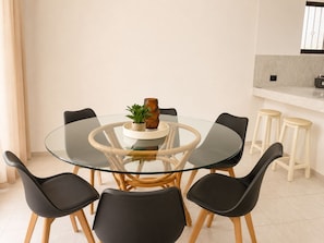 A modern dining area with a glass table surrounded by black chairs, a small potted plant, and a decorative vase. - Gupy 26 - 3BR house steps from de beach  (Cancún)