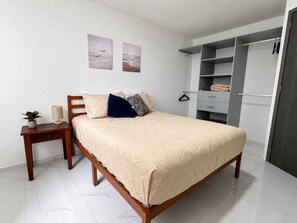 Ein Schlafzimmer mit einem Bett, einem Nachttisch, einer Lampe und einem Kleiderschrank.