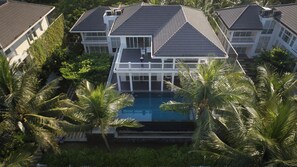 A large house with a swimming pool surrounded by palm trees. - Koaniva Premier Village Danang (Ngu Hanh Son)
