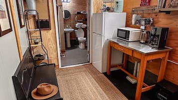 Una cocina compacta con interior de madera, un cartel que dice 'The Good Old Days' y comodidades básicas como refrigerador, microondas y cafetera.