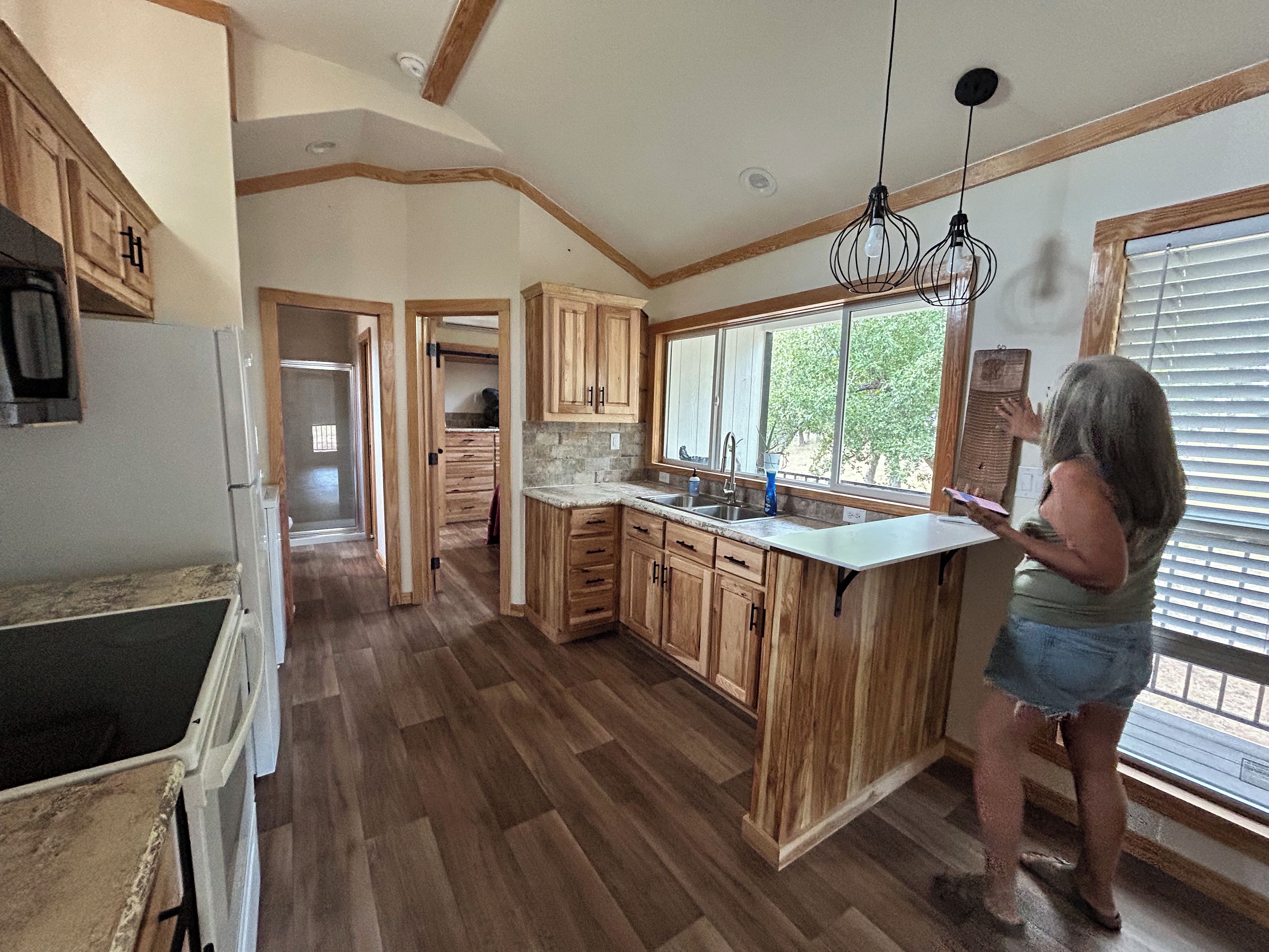 Une cuisine avec des meubles de rangement en bois, un plan de travail et une fenêtre avec des stores.