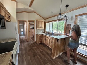 A kitchen with wooden cabinets, a countertop, and a window with blinds. - Cozy 1-bedroom house in adorable Harper with cool AC (Harper)