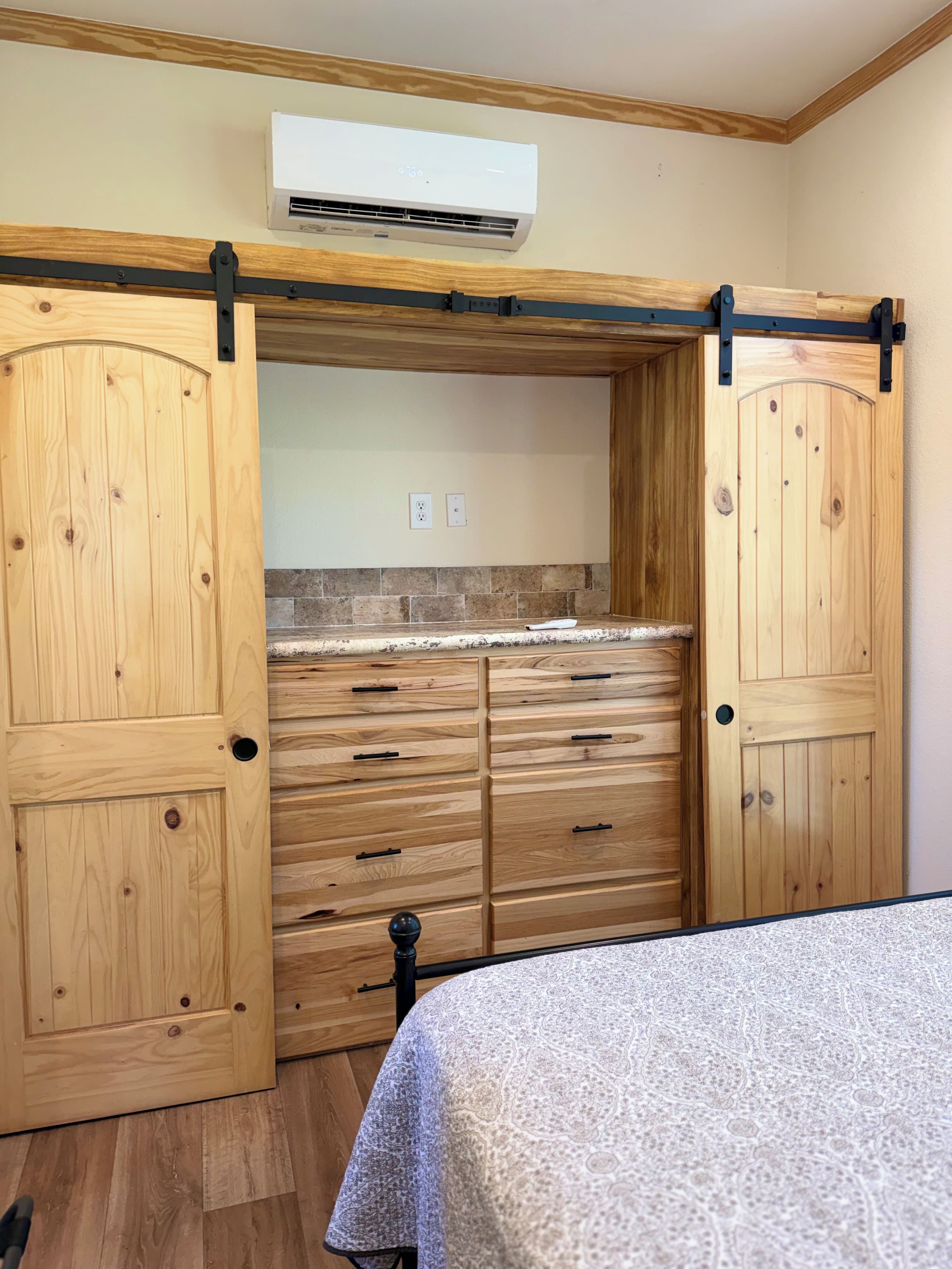 Ein Zimmer mit einem Bett, einem Holzschrank und einer Klimaanlage.