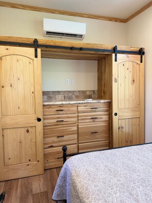 Ein Zimmer mit einem Bett, einem Holzschrank und einer Klimaanlage.