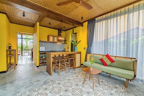 A spacious living area with a sofa, a dining table, and a kitchen in the background. - May Villa 6BR Beachside An Bang Beach Hoi An by Beachside Boutique Homes (Đà Nẵng)