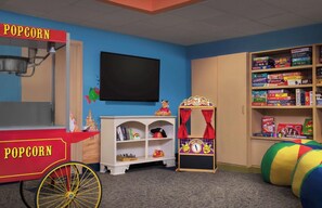 Una habitación con un carrito de palomitas, televisor, estantería y área de juegos con piscina de pelotas.