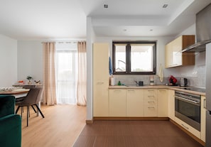 Una cocina moderna con armarios de madera, horno empotrado y ventana con cortinas.