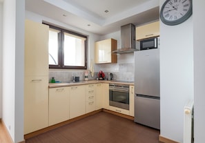 Una cocina moderna con horno empotrado, microondas y refrigerador de acero inoxidable.