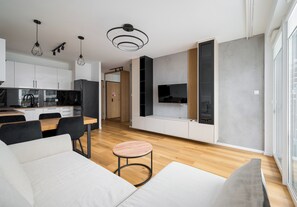 Un salon moderne avec un canapé, une table ronde et un téléviseur fixé au mur.