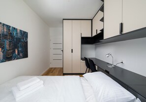 Une chambre moderne avec un lit, un bureau et une chaise. Une porte donne accès à une salle de bain.