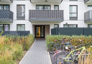 Un bâtiment moderne doté d’une entrée centrale, d’un espace extérieur abrité et de vélos garés à l’extérieur.