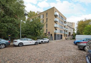Ein mehrstöckiges Gebäude mit Ziegelverkleidung, eine gepflasterte Straße und geparkte Autos.