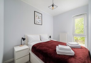 A bedroom with a bed, bedside tables, a window, and a hanging light fixture. - Olszowa 14 Riverside Apartment (Warszawa)