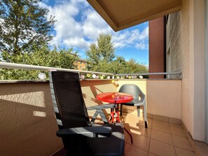 Ein Balkon mit einem Stuhl, einem kleinen Tisch und einer Geländer.