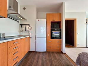 Una cocina compacta con refrigerador, horno y armarios de madera.