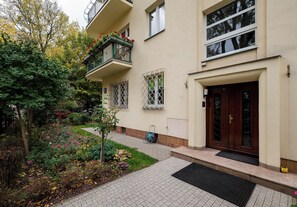 A residential building with a garden entrance, a wooden door, and a balcony with flowers. - Saska Kępa Standard Apartment (Warszawa)