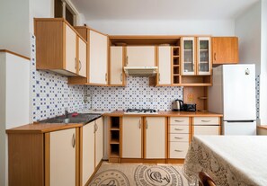A compact kitchen with wooden cabinets, a gas stove, a sink, and a refrigerator. - Saska Kępa Standard Apartment (Warszawa)