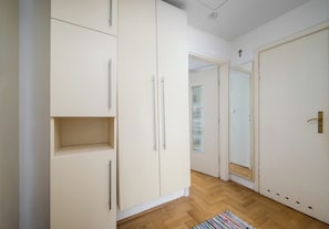 A hallway with a wardrobe, a door with a brass handle, and a patterned rug on the floor. - Saska Kępa Standard Apartment (Warszawa)