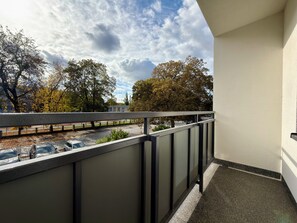 A balcony with a view of parked cars and trees. - Przestrzenna Comfort Apartment (Wrocław)