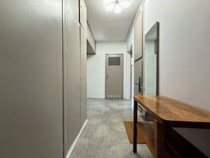 A hallway with a wooden bench, a door at the end, and a light fixture on the ceiling. - Przestrzenna Comfort Apartment (Wrocław)