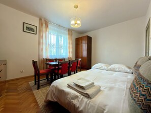 Ein Hotelzimmer mit einem Bett, einem Schreibtisch mit Stühlen, einem Kleiderschrank und einem Fenster mit Vorhängen.