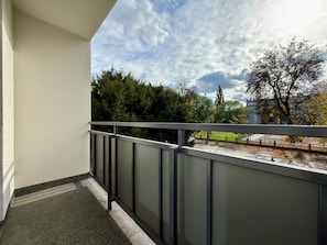 A balcony with a metal railing overlooking a park with trees and a clear sky. - Przestrzenna Comfort Apartment (Wrocław)