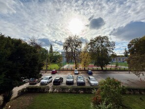Ein Parkplatz mit mehreren Autos, umgeben von Bäumen und einem Gebäude im Hintergrund.