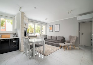 A modern kitchen with a dining area, a sofa, and a chair. There are windows, a door, and artwork on the wall. - Praga Ostrobramska Lavish Apartment (Warszawa)