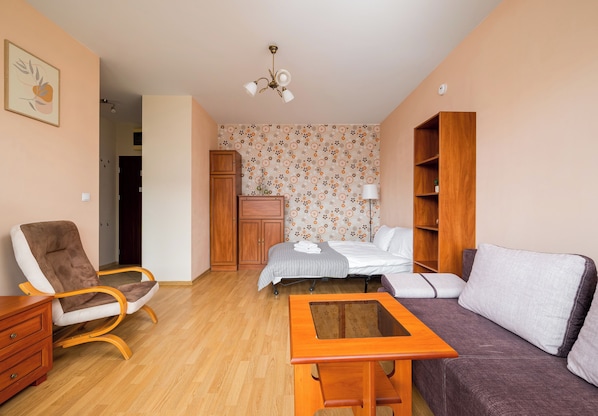Uma sala de estar mobiliada com sofá, poltrona, armário de madeira e uma mesa pequena.