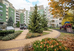 Ein Wohngebiet mit Mehrfamilienhäusern, einem gepflasterten Weg und einem Spielplatz.