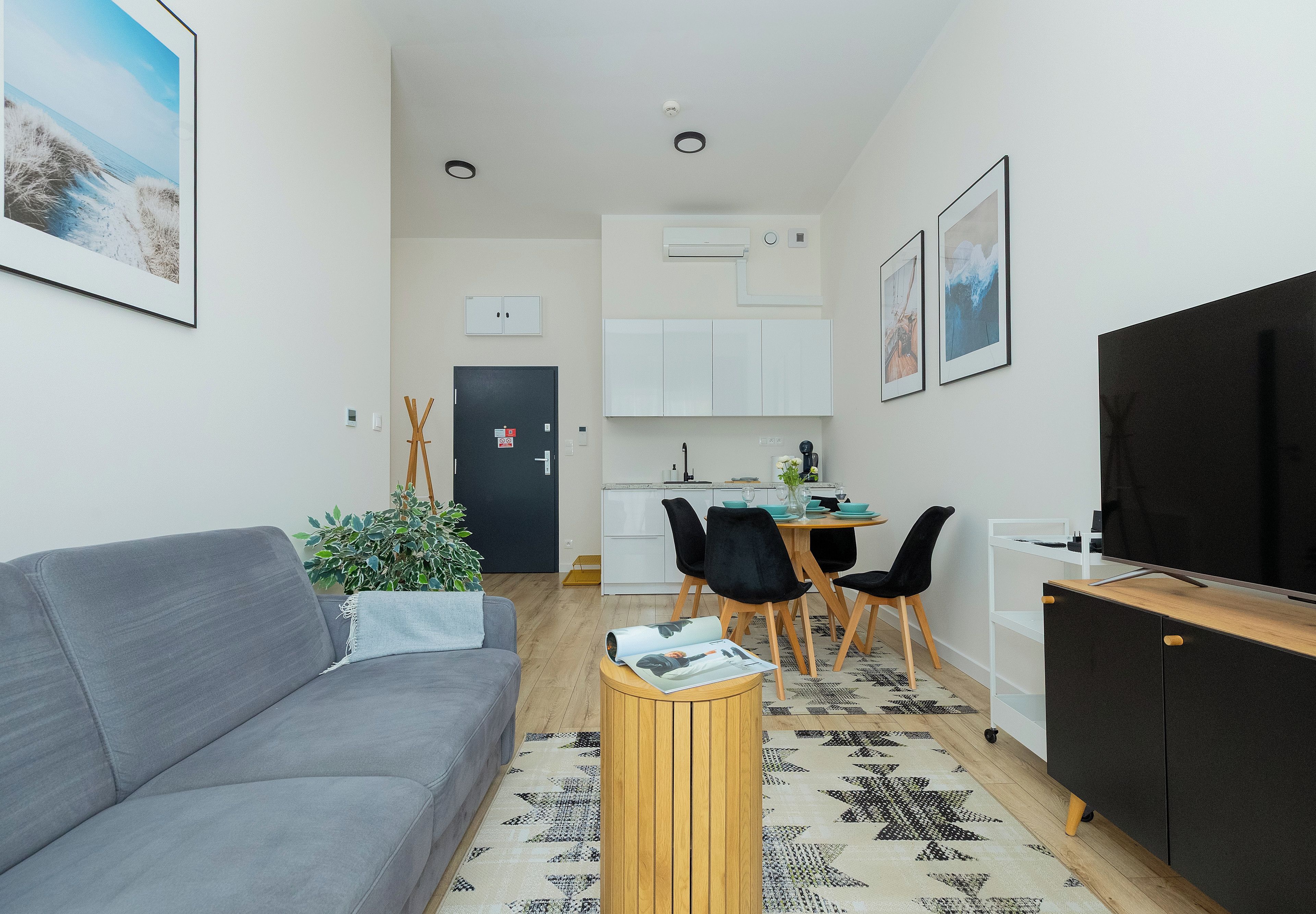 Ein kompakter Wohnbereich mit Sofa, Esstisch, Stühlen, Fernseher und Küchenzeile.
