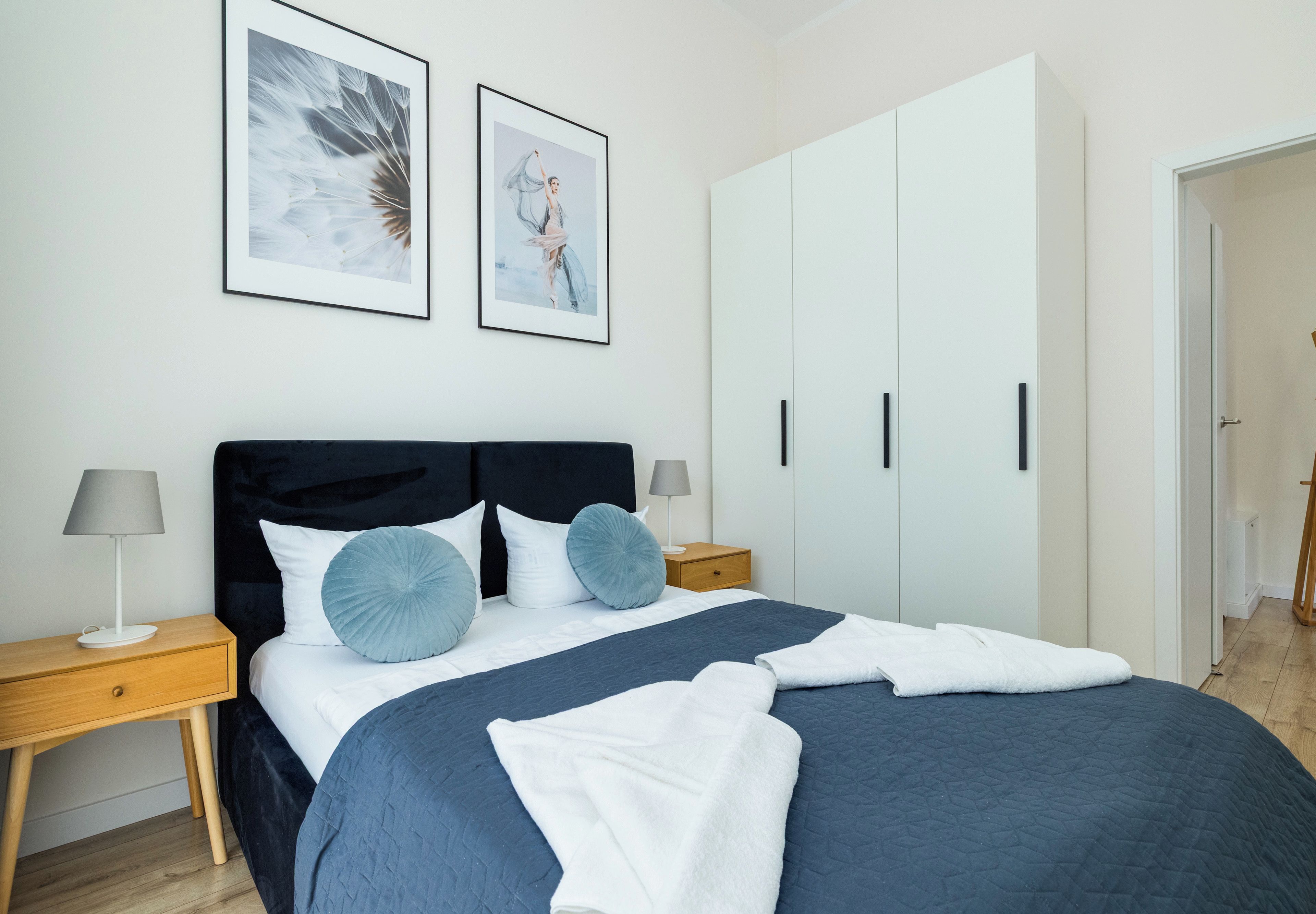 Ein Schlafzimmer mit einem Bett, zwei Nachttischen, einem Kleiderschrank und zwei gerahmten Bildern an der Wand.