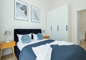 Ein Schlafzimmer mit einem Bett, zwei Nachttischen, einem Kleiderschrank und zwei gerahmten Bildern an der Wand.