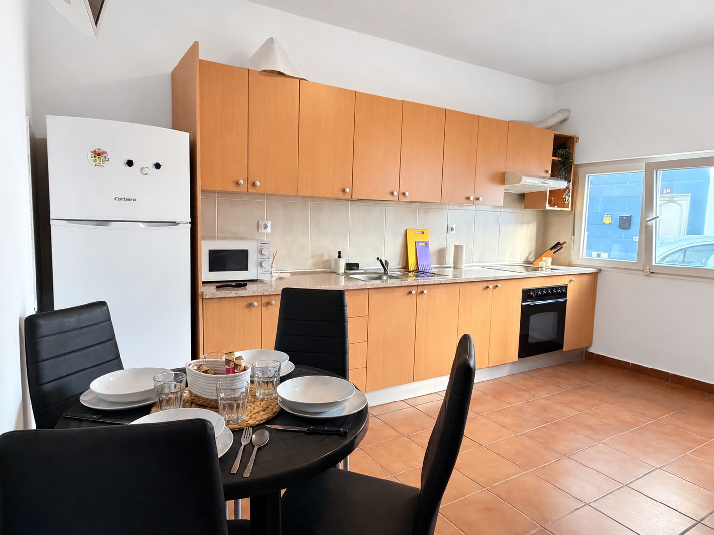A compact kitchen with wooden cabinets, a microwave, and a dishwasher.
