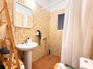 Une salle de bain avec un lavabo blanc, un miroir et un espace douche.