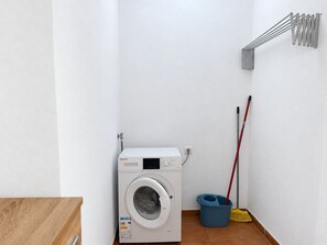 A compact laundry room with a front-loading washing machine, a mop, and a broom. - New Listing (Puerto del Rosario)
