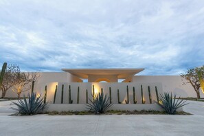 A modern building with a flat roof, a central entrance, and a series of vertical light fixtures. - Modern Ocean View 2BR Condo Resort-Style Pool, Gym & Prime Cabo Location (Cabo San Lucas)