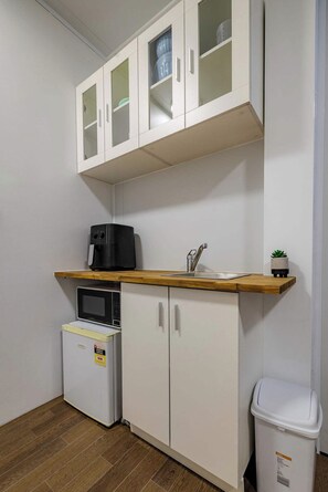 A compact kitchen with white cabinets, a microwave, a coffee maker, and a trash bin. - Modern 2BR Hideaway Near Coffs Harbour CBD (Coffs Harbour)