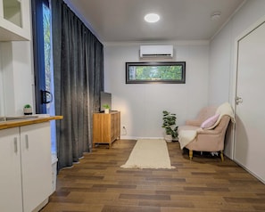 A modern living space with a kitchen area, a seating area with a sofa, a small table, and a potted plant. - Modern 2BR Hideaway Near Coffs Harbour CBD (Coffs Harbour)