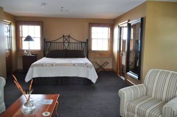 A bedroom with a bed, a nightstand, a lamp, a chair, and a window.