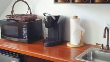 A compact kitchenette with a microwave, coffee maker, and a small sink.