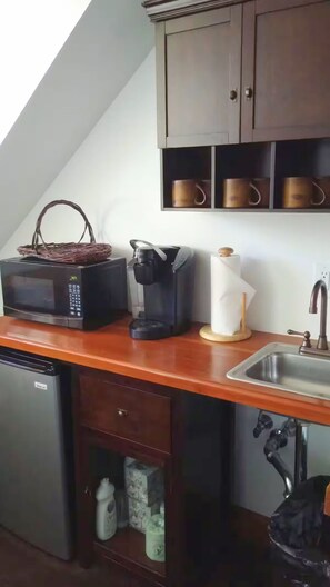 A compact kitchenette with a microwave, coffee maker, and a small sink.