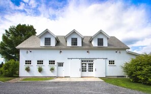 A white building with a symmetrical facade, a central entrance, and a driveway leading to the front. - East Barn Suite at Hubbell Homestaead - Mountain Views & Jetted Tub (Bennington)
