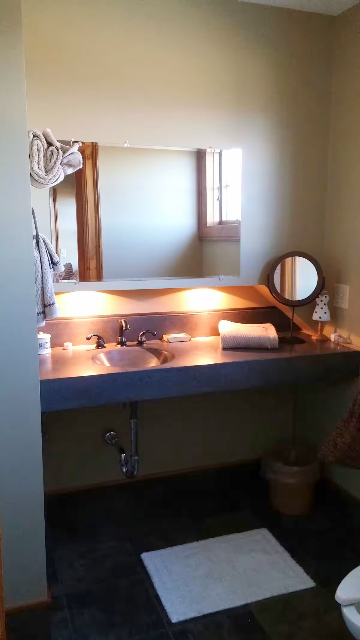 Ein Badezimmer mit Waschbecken, Spiegel, Handtuch und kleinem Fenster.