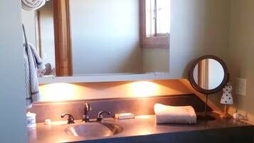 Ein Badezimmer mit Waschbecken, Spiegel, Handtuch und kleinem Fenster.