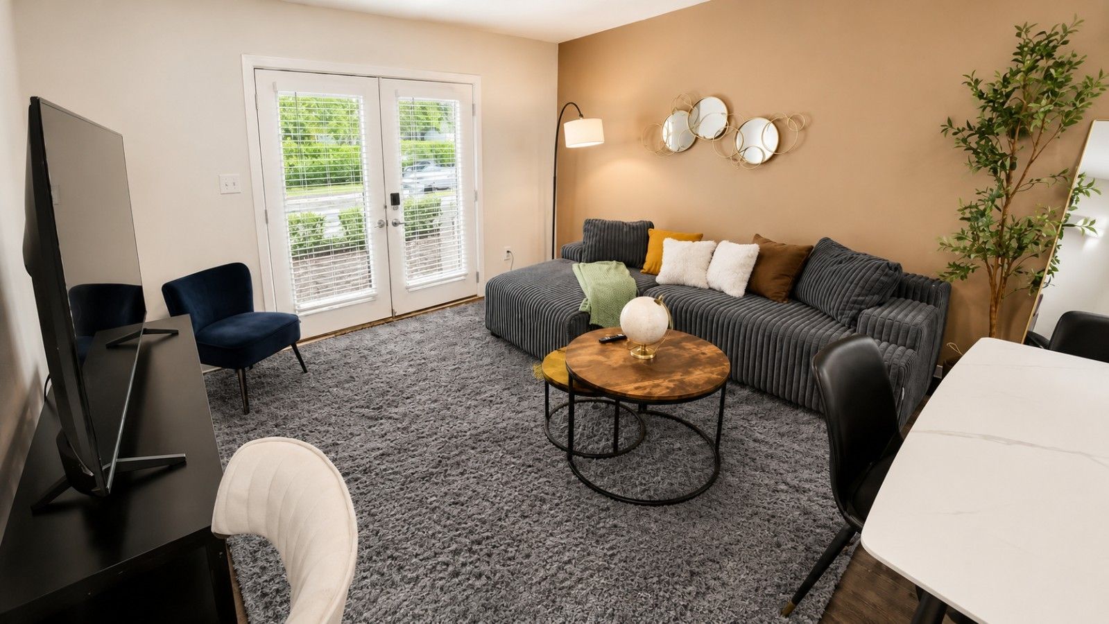 A modern living room with a grey sofa, a round coffee table, and a flat-screen TV.